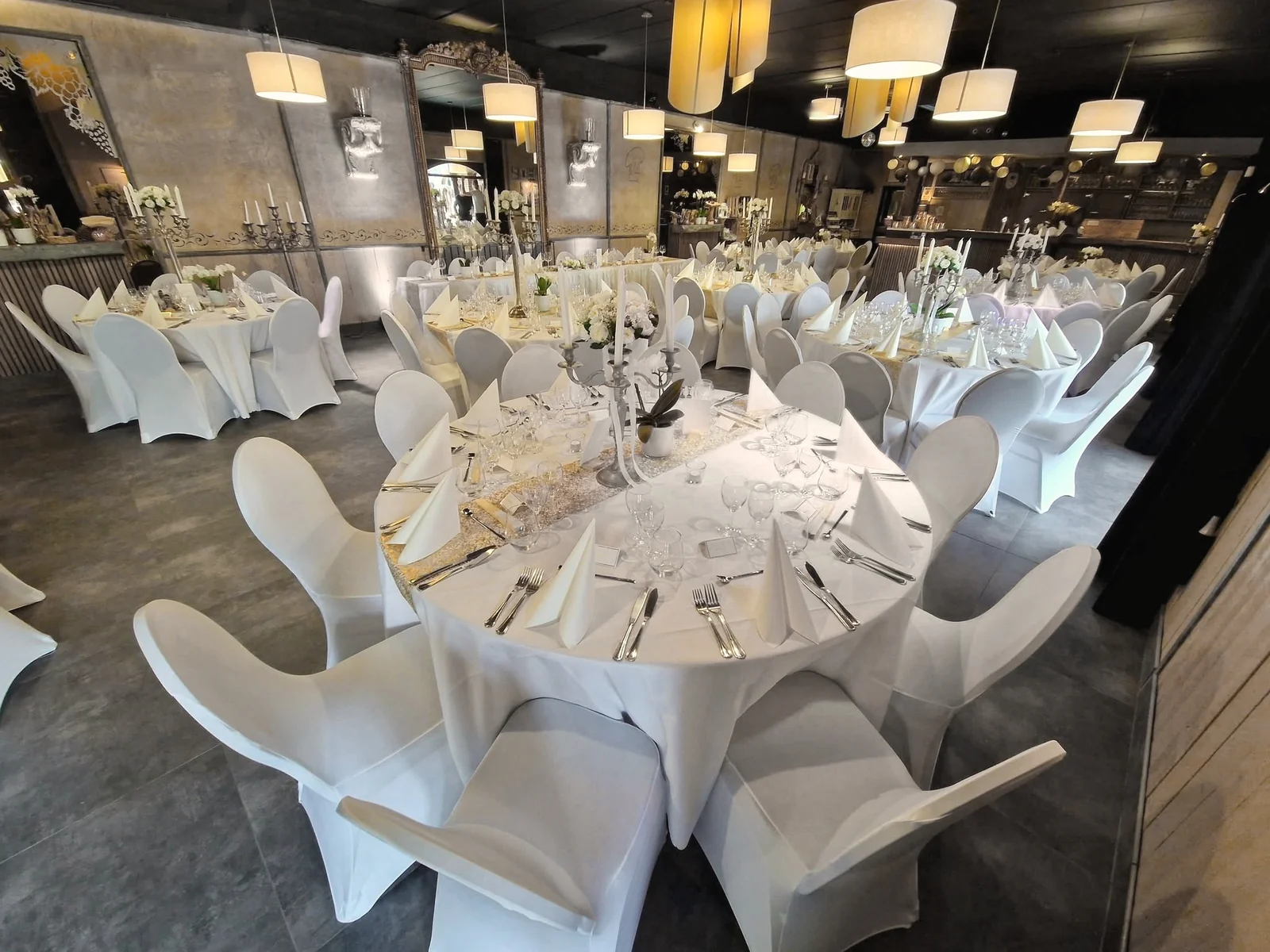 La grande salle dressée de tables rondes pour un mariage